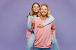 © ViDi Studio - Young couple two friends family man woman wear pink blue casual clothes together giving piggyback ride to joyful, sit on back show thumb up isolated on pastel plain purple background studio portrait.