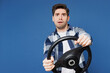 © ViDi Studio - Young scared fearful frightened sad man wear shirt white t-shirt casual clothes hold steering wheel driving car look camera isolated on plain blue cyan background studio portrait. Lifestyle concept.