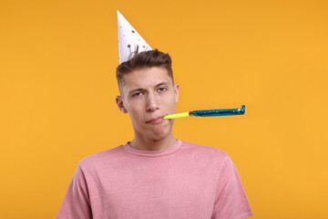 Poster - Young man in party hat with blower on orange background