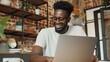 © liliyabatyrova - A man is smiling while using a laptop in a room with a brick wall