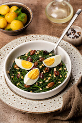 Wall Mural - Spring Italian Salad. Sauteed Agretti with Taggiasca olives, pinoli or pine nut, and boiled eggs. Vertical image.