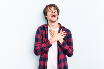 Poster - Young caucasian man isolated on blue background laughing keeping hands on heart, concept of happiness.