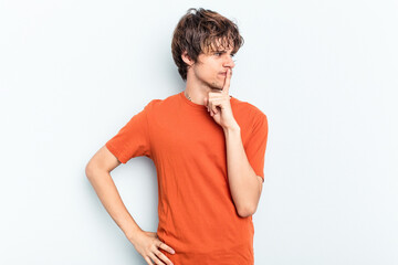 Wall Mural - Young caucasian man isolated on blue background keeping a secret or asking for silence.