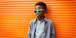 Boy with sunglasses, casual in front of orange wall with space for text
