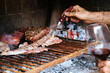 Man with a red wine cup making a barbeque, bbq meat cooking on grill. Traditional Asado of Argentina, Paraguay y Uruguay.