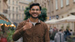 Happy joyful young smiling Indian Arabian ethnic male client customer man student businessman show like hand thumb up gesture good results excellent agree recommend approve symbol outdoors city street