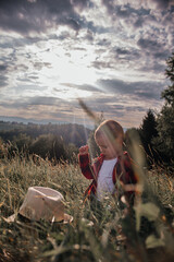 Wall Mural - boy of two years old in a hat and red shirt in a field