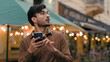 Nervous lonely Indian Arabian ethnic male businessman guy looking around feeling lost. Man holding smartphone use mobile electronic map geolocation app trying find location outside city evening street
