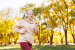 Happy senior woman in headphones listening music while jogging outside in city park.