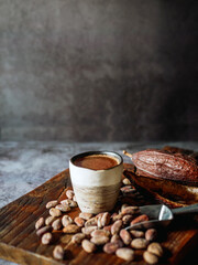 Natural craft cocoa drink on wooden tray, organic healthy chocolate drink with brown cocoa beans and dry cacao pod