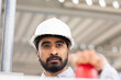 © Image Source - A focused man wearing a white hard hat is looking intently at something, pressing the red button