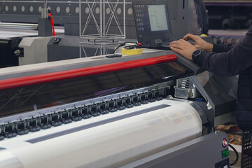 Wall Mural - a man adjusts the printing process on a large format printing machine