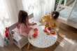 Cute little girls playing with plastic toy kitchen indoors at home.