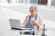 Elderly Senior Business woman with gray short hair, Mature female freelancer works on laptop, looks at computer at table in outdoor cafe portrait. Age in Tech