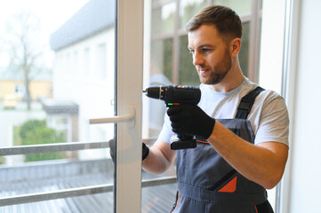 worker installing plastic window indoors.