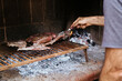 Man cooking the meat on the fire, making the barbecue on the coals in the grill of his house. Traditional Asado of Argentina, Chile, Paraguay y Uruguay.