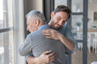 Caring cute caucasian adult son hugging embracing his old elderly senior father showing him love and support. Family time, happy father`s day! I love you, dad!