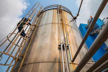 Wall Mural - Top view male worker climbs up the ladder inspection stainless tank work at height