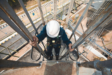 Wall Mural - Top view male worker climbs up the ladder inspection stainless tank work at height