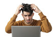 young man sits in front of a laptop with her hand on her head in a gesture of frustration isolated on a transparent background
