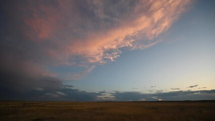 Wall Mural - time lapse of a cloud brightly lit by the setting sun. the scene is set in a flat dry prairie