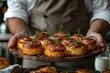 Chef holds a baking sheet with freshlybaked buns or pies  on the background of a bread factory or bakery