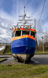 Fototapeta  - A small fishing boat standing on the shore near the marina, Sztutowo, Northern Poland