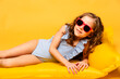 Cute little girl in blue swimsuit and sunglasses on yellow inflatable mattress on yellow background. Summer vacation, travel, resort. Summer sea rest concept. high quality photo