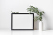 Frame mockup in white minimalistic interior with botanical decor, blank mockup for artwork