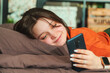Young beautiful smiling woman with phone on bed.