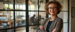 © Darya - A professional woman with curly hair and glasses stands confidently with arms crossed in a contemporary office setting, embodying experience and leadership.