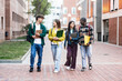 Group of student friends walking on college campus, chatting and laughing after university classes