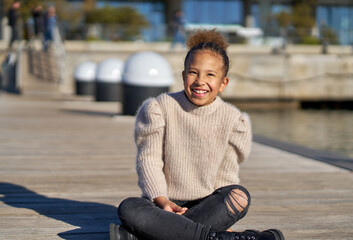 A young girl is sitting on a wooden pier