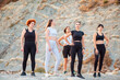 Group of Caucasian fit women in sportswear pose standing on rock. Concept of girl power and sports lifestyle