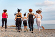 Wellness. Back view of group of jogging women at pebble beach. Concept of healthy lifestyle and cardio fitness
