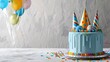 Blue birthday cake presents hats and colorful balloons over light grey