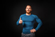 Handsome athletic muscular man showing a thumb up. Black background. Copy space. Sports advertising concept