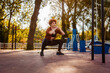 Mid adult Caucasian woman squatting hardly in sports park. Copy space. Concept of aerobics and fitness
