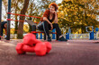 Mid adult Caucasian smiling woman is sitting on playground and listening to music with headphones. Low angle view. Copy space. Concept of fitness and training