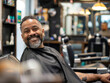 A smiling mansitting in a barber chair. 