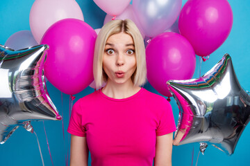 Wall Mural - Photo portrait of attractive young woman amazed air balloons dressed stylish pink clothes isolated on blue color background