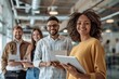 © ChaoticMind - Group of young, diverse professionals holding tablets and smiling, standing in a modern office space