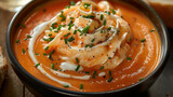 Fototapeta Most - A rich, creamy bowl of lobster bisque, with a swirl of cream and a sprinkle of chives on top. The image emphasizes the smooth texture.
