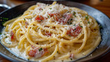 Fototapeta Most - A plate of classic spaghetti carbonara, with creamy sauce, crisp pancetta, and a sprinkling of Parmesan cheese. The strands of spaghetti are captured in detail, with the sauce.