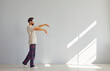 Full length portrait of young sleepwalker man in pajamas suffering from sleepwalking in sleep mask isolated on gray wall background. Somnambulism, insomnia and sleep problems concept.