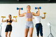 Low angle view of three athletic people lifting weights in a gym class