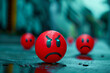 Three red angry faces are sitting on a wet surface. The faces are all different sizes and are positioned in a row. Scene is one of anger and frustration