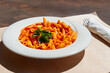 Penne arrabiata - traditional italian pasta with spicy sauce on a table