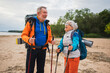 Hiking tourism adventure. Senior couple man woman enjoying outdoor recreation hiking on beach. Happy old people backpackers hikers enjoy walking hike trekking tourism active vacation beauty of nature