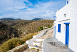 Fototapeta  - View of Kastro village buildings from coastal promenade with mountain ladscape in background, Sifnos island, Greece